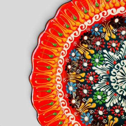 Orange ceramic plate detail, red scalloped rim, painted floral dotwork and yellow/green accents