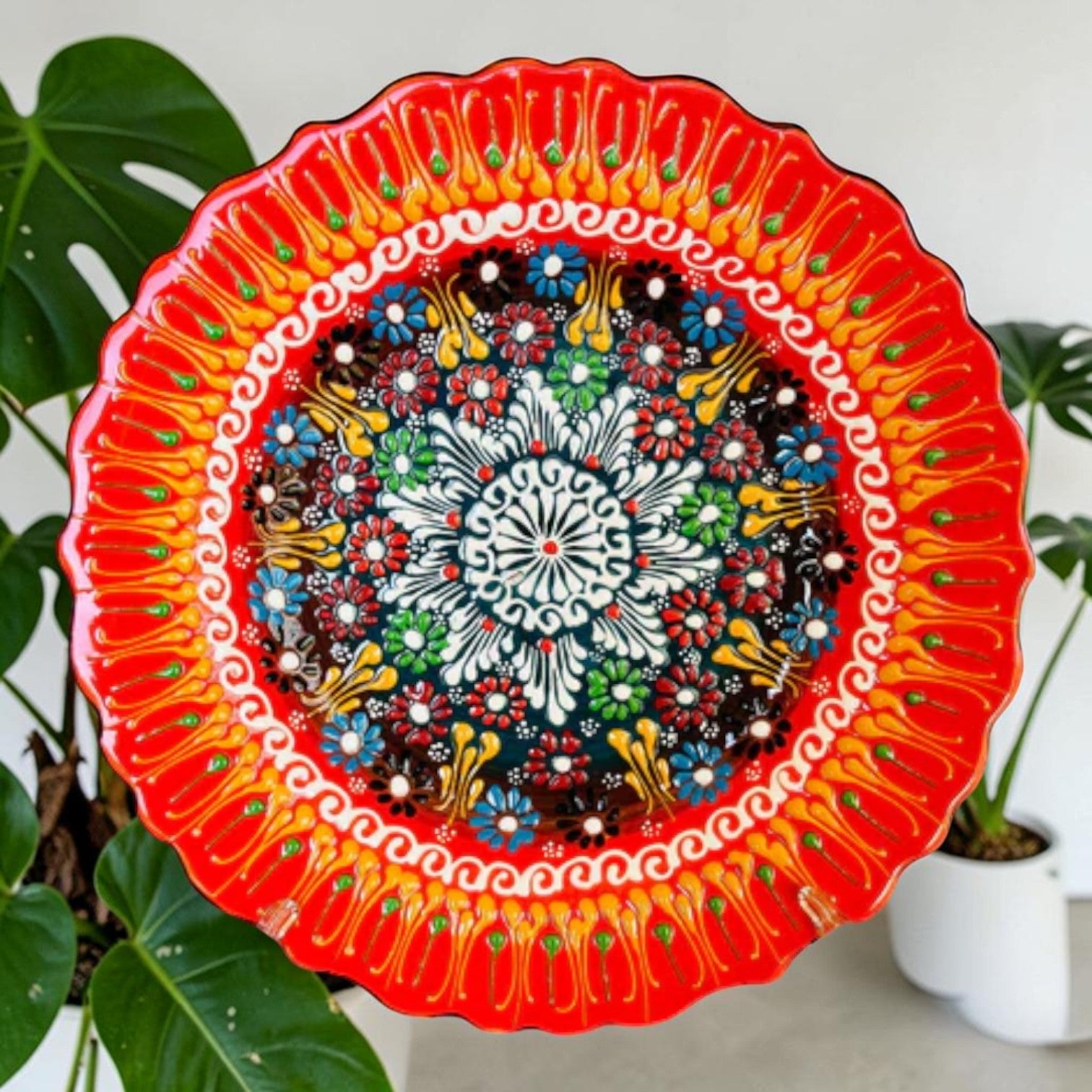 Orange ceramic wall plate with bright floral dot mandala center and scalloped edge