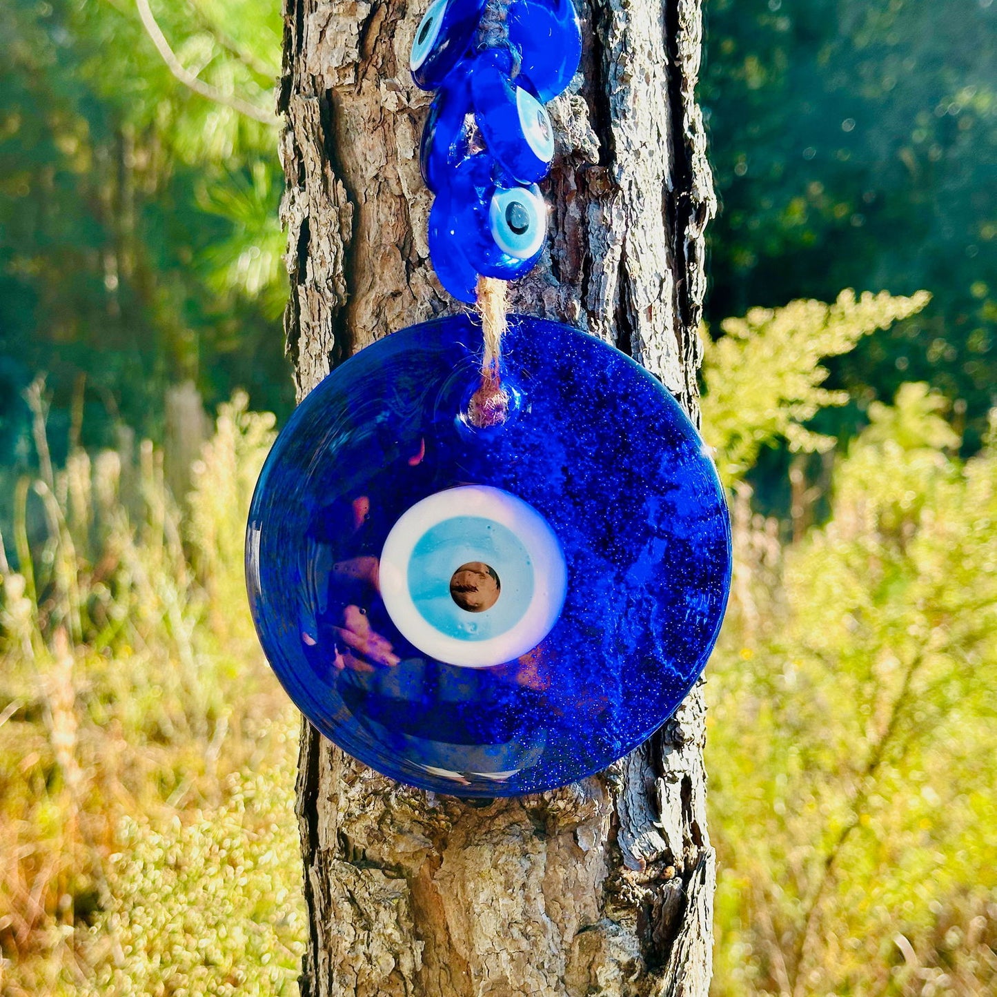 Close-up blue evil eye glass disc charm with white and light blue eye ring