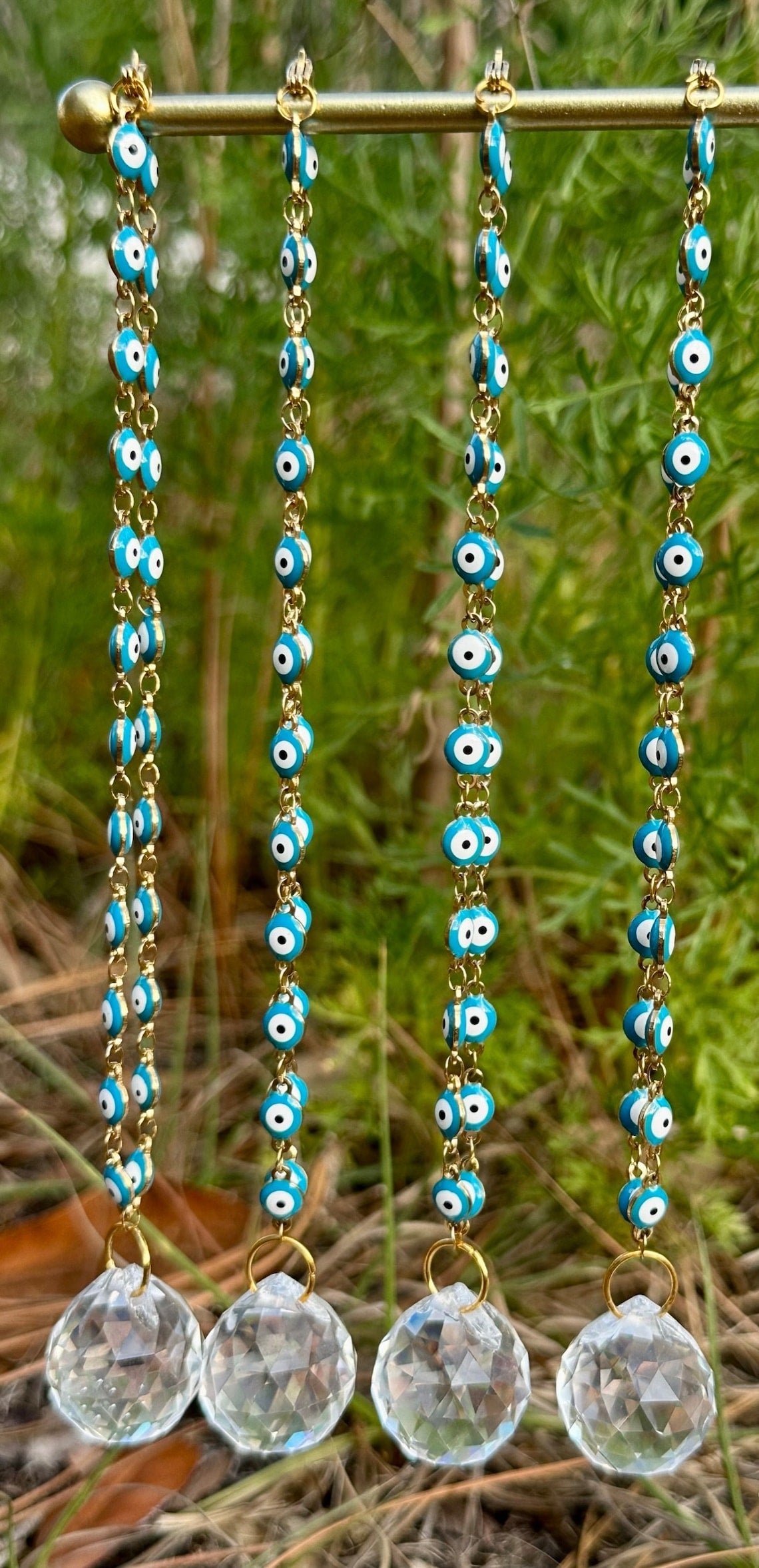 Evil eye rearview mirror charm with gold chain strands, blue beads, and clear crystal discs