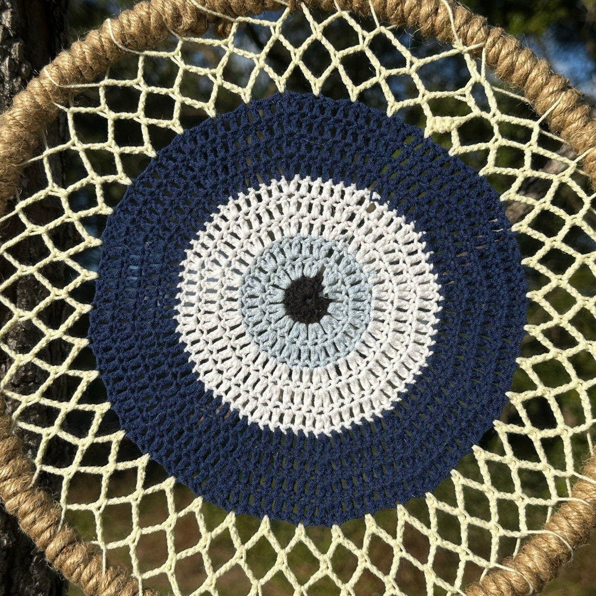 Round macrame evil eye wall hanging with navy and white concentric pattern