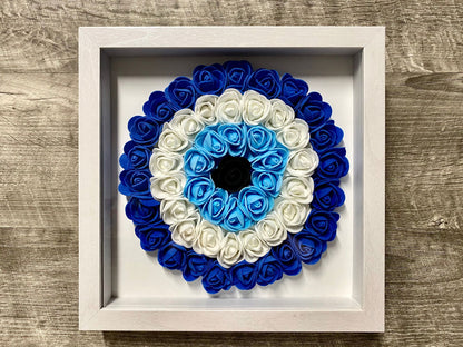 White framed evil eye wall hanging with blue-and-white rosette floral wreath