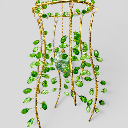 Hanging gold metal suncatcher with green beads and a clear faceted stone center