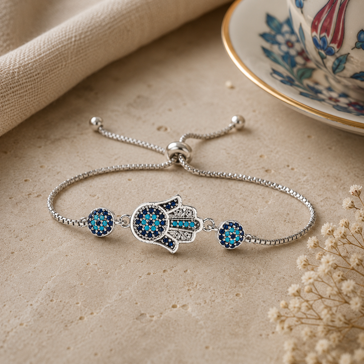 Silver-tone charm bracelet with blue evil-eye CZ beads and a hamsa center charm