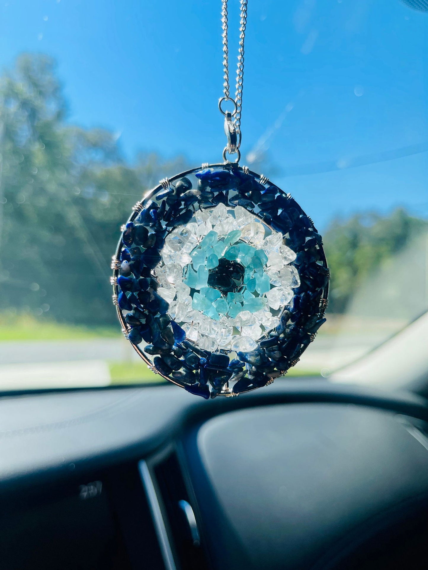 Evil eye pendant with circular blue stone frame, light aqua center, hanging silver chain