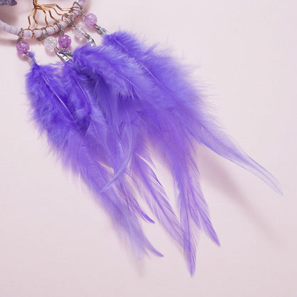 Close-up of purple dreamcatcher feathers with bead charms and gold-toned details