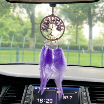Purple dreamcatcher hanging from a car rearview mirror, round amethyst tree design with feathers
