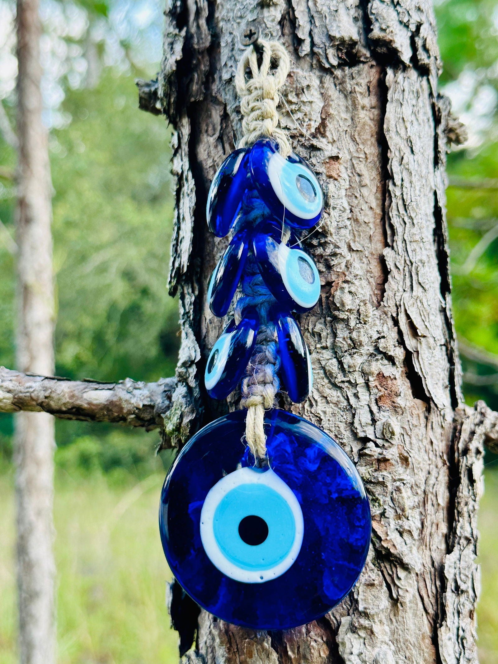 Blue evil-eye wall hanging with dark macrame, small charms above a large round blue bead