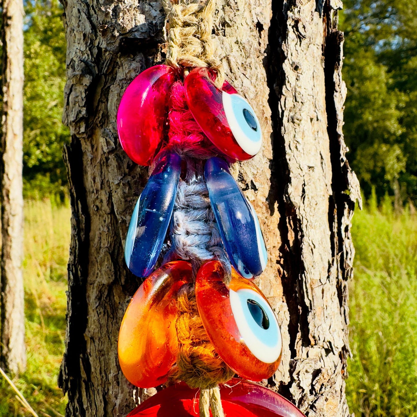 Macrame evil-eye wall hanging with pink, blue, and orange resin eye beads on twine