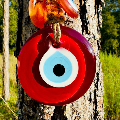 Red resin evil-eye bead wall hanging with white eye ring and black pupil on rope