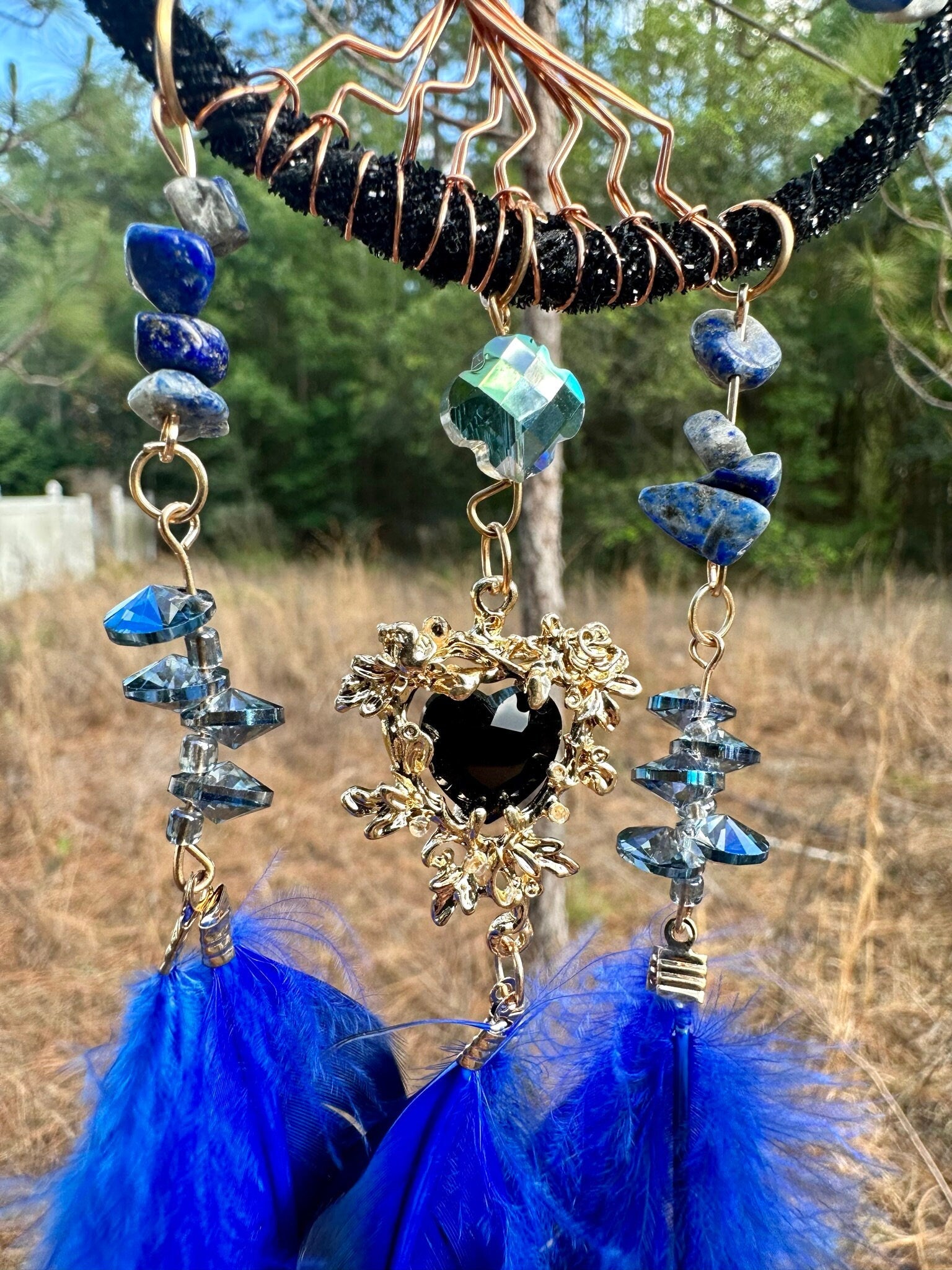 Blue and black beaded dreamcatcher with copper web, blue feathers, and heart charm