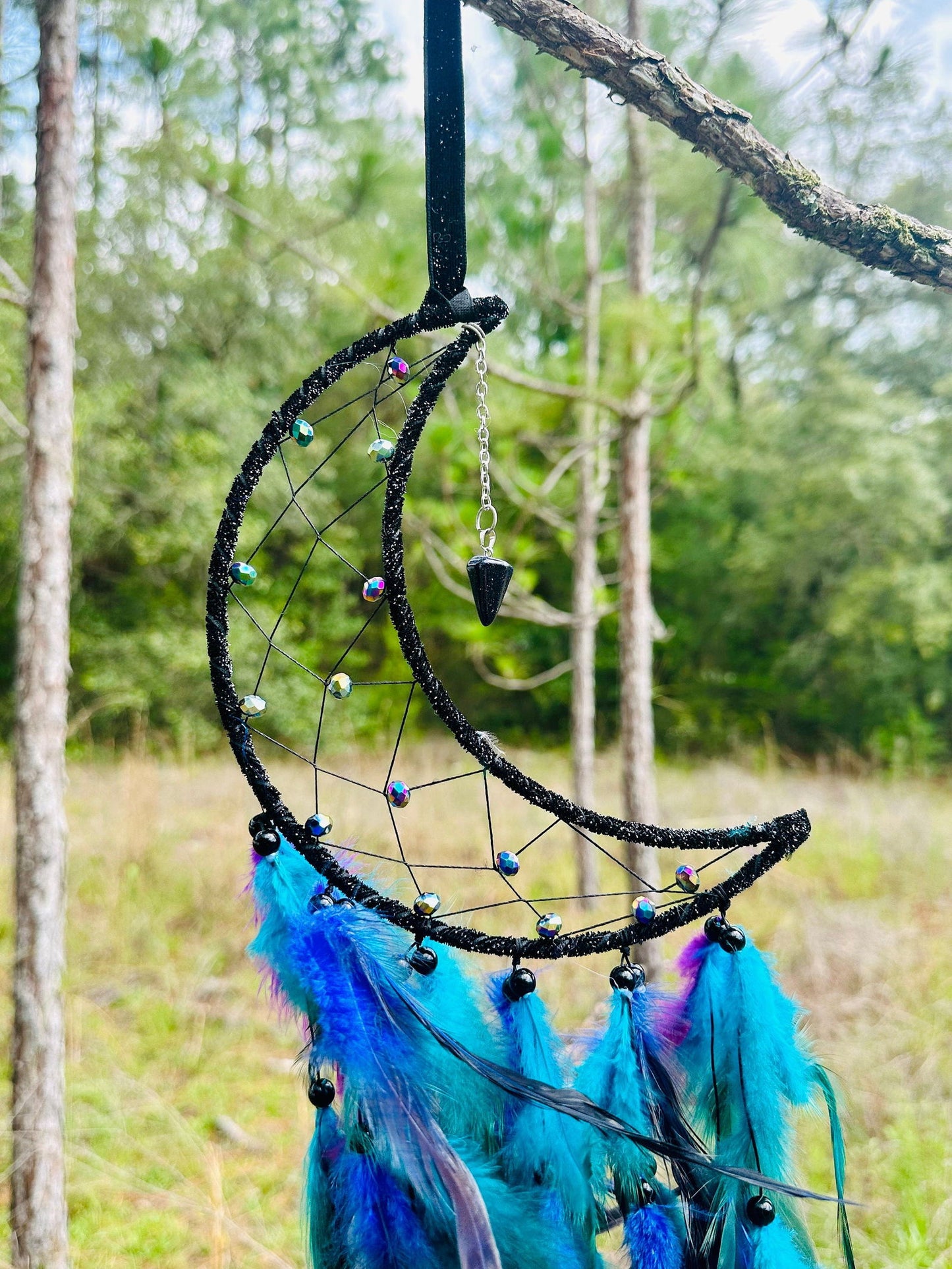 Crescent moon dream catcher with beaded net, hanging charm, and bright blue feathers