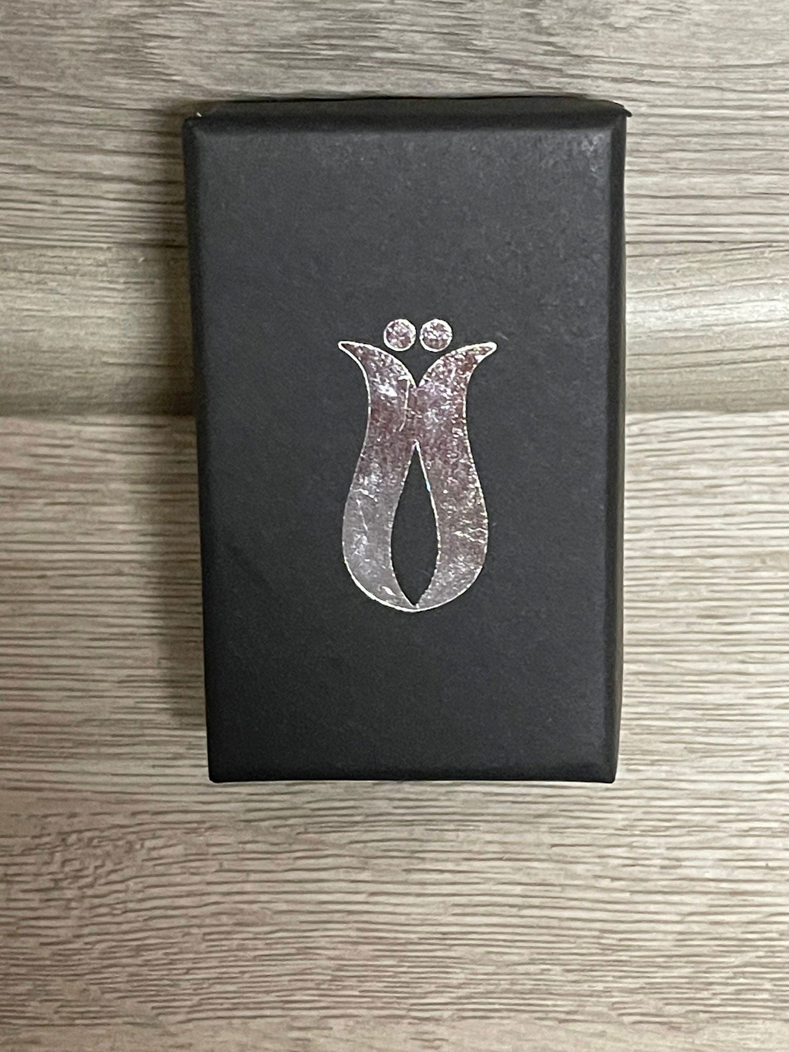 Gift box with silver evil eye cat-shaped pendant graphic