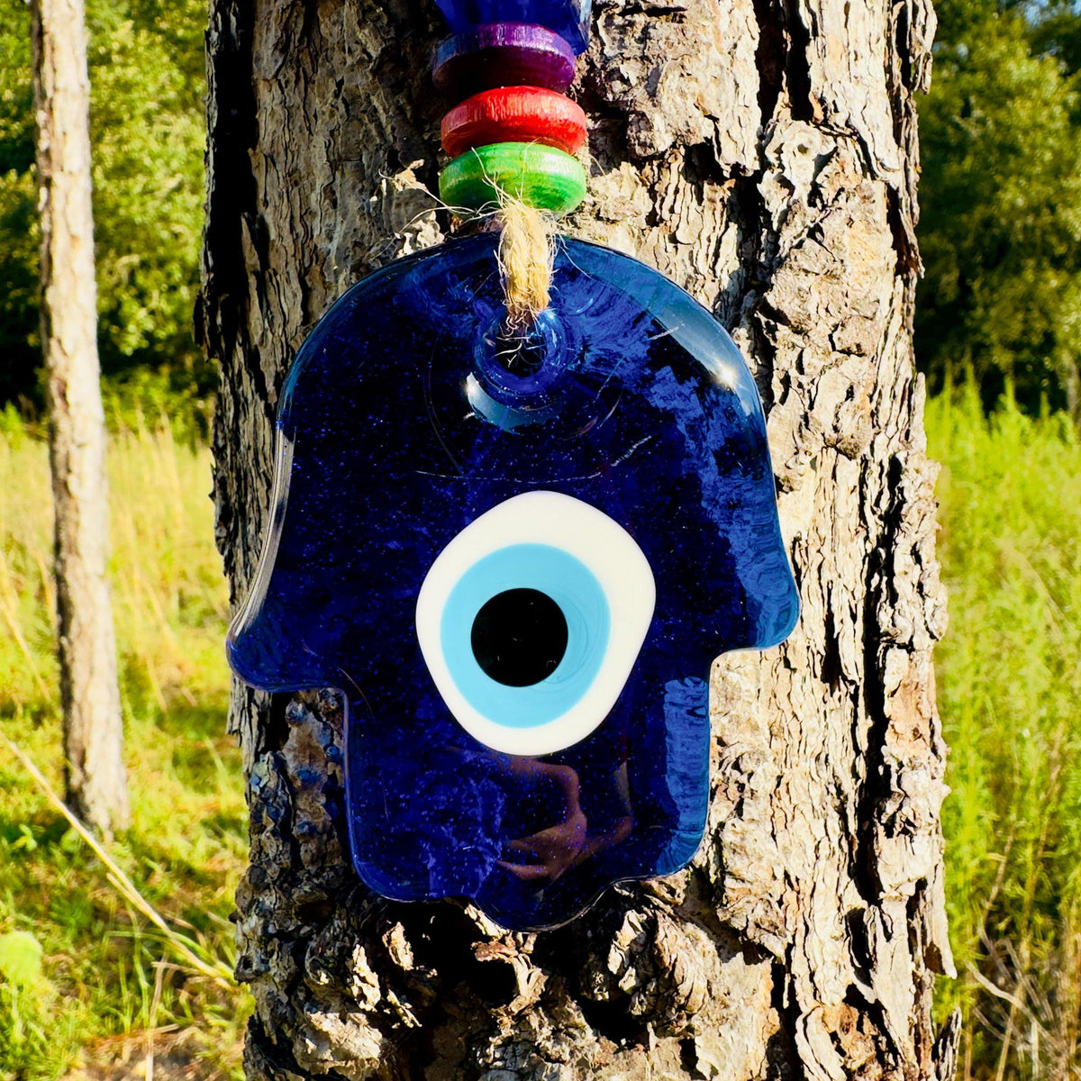 Blue hamsa charm with large white evil eye on twine wall hanging