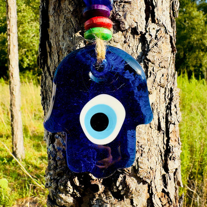 Blue hamsa charm with large white evil eye on twine wall hanging