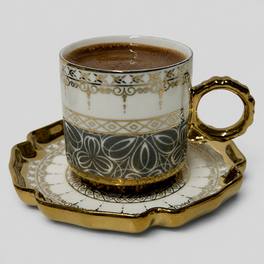 Turkish coffee cup filled with coffee on matching saucer, white charcoal porcelain, gold rim