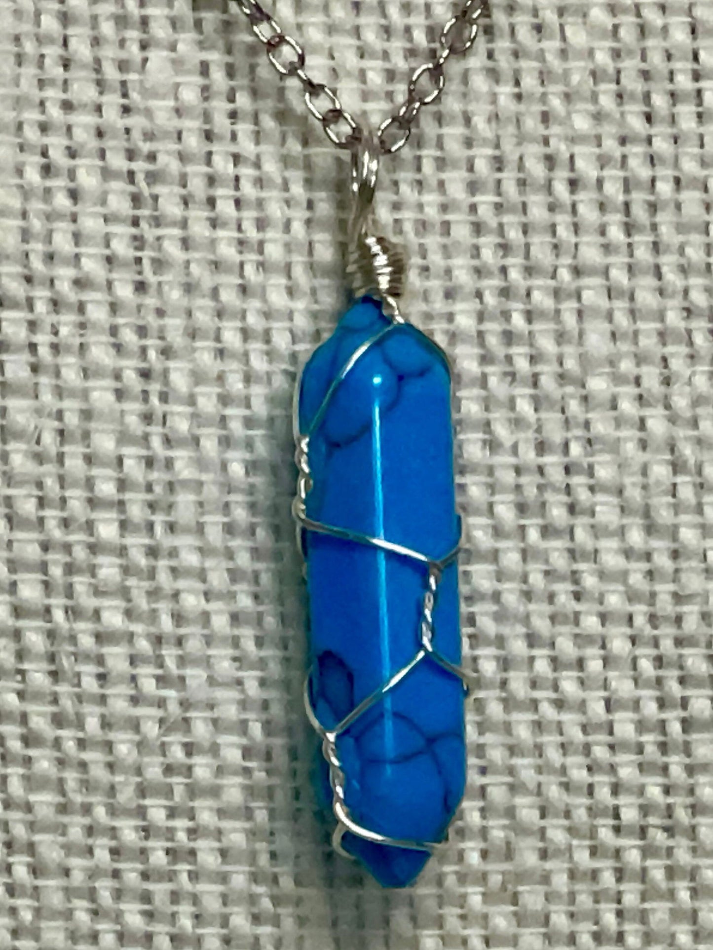 Silver wire-wrapped gemstone necklace with bright blue crystal point pendant
