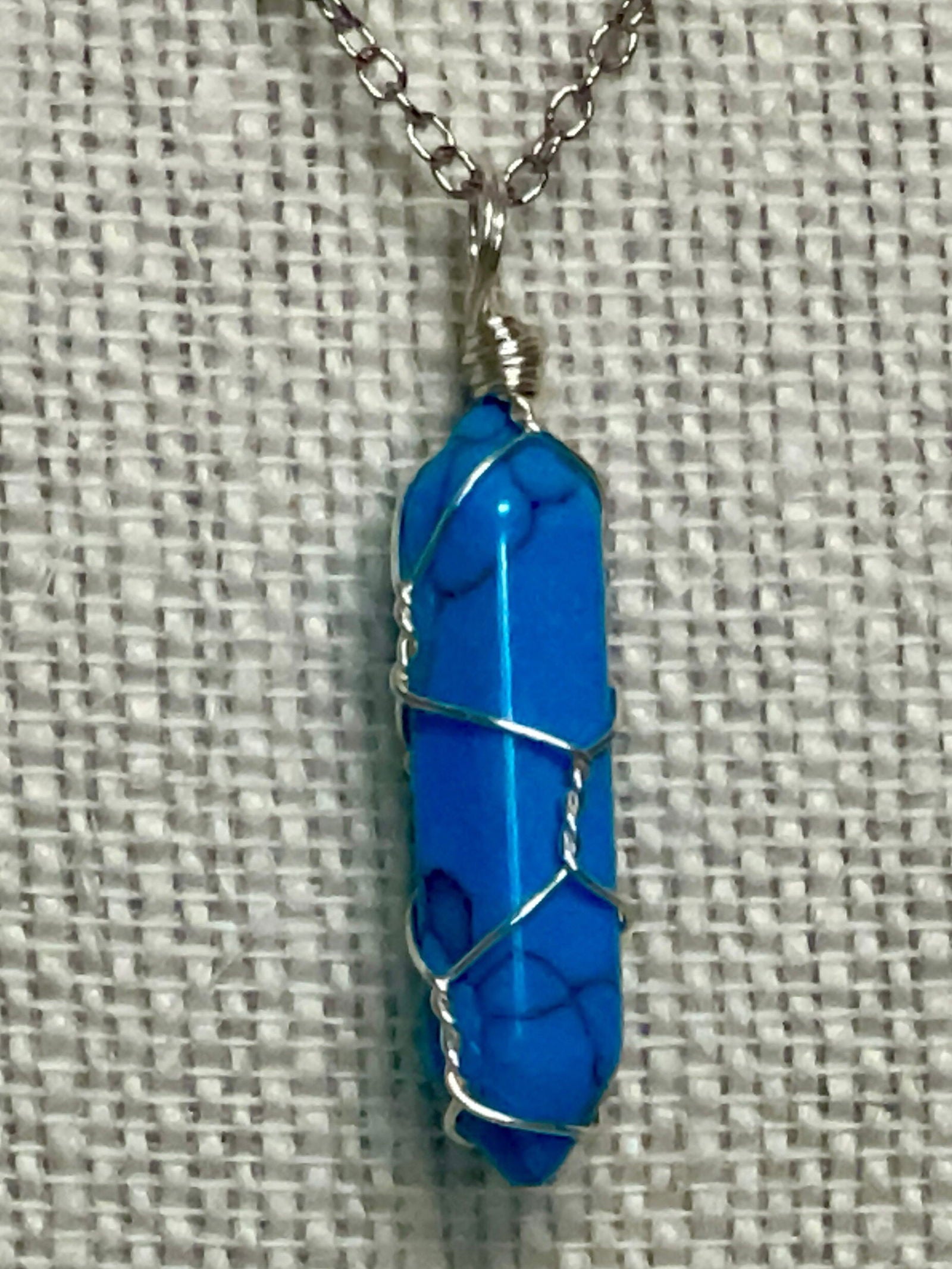 Silver wire-wrapped gemstone necklace with bright blue crystal point pendant