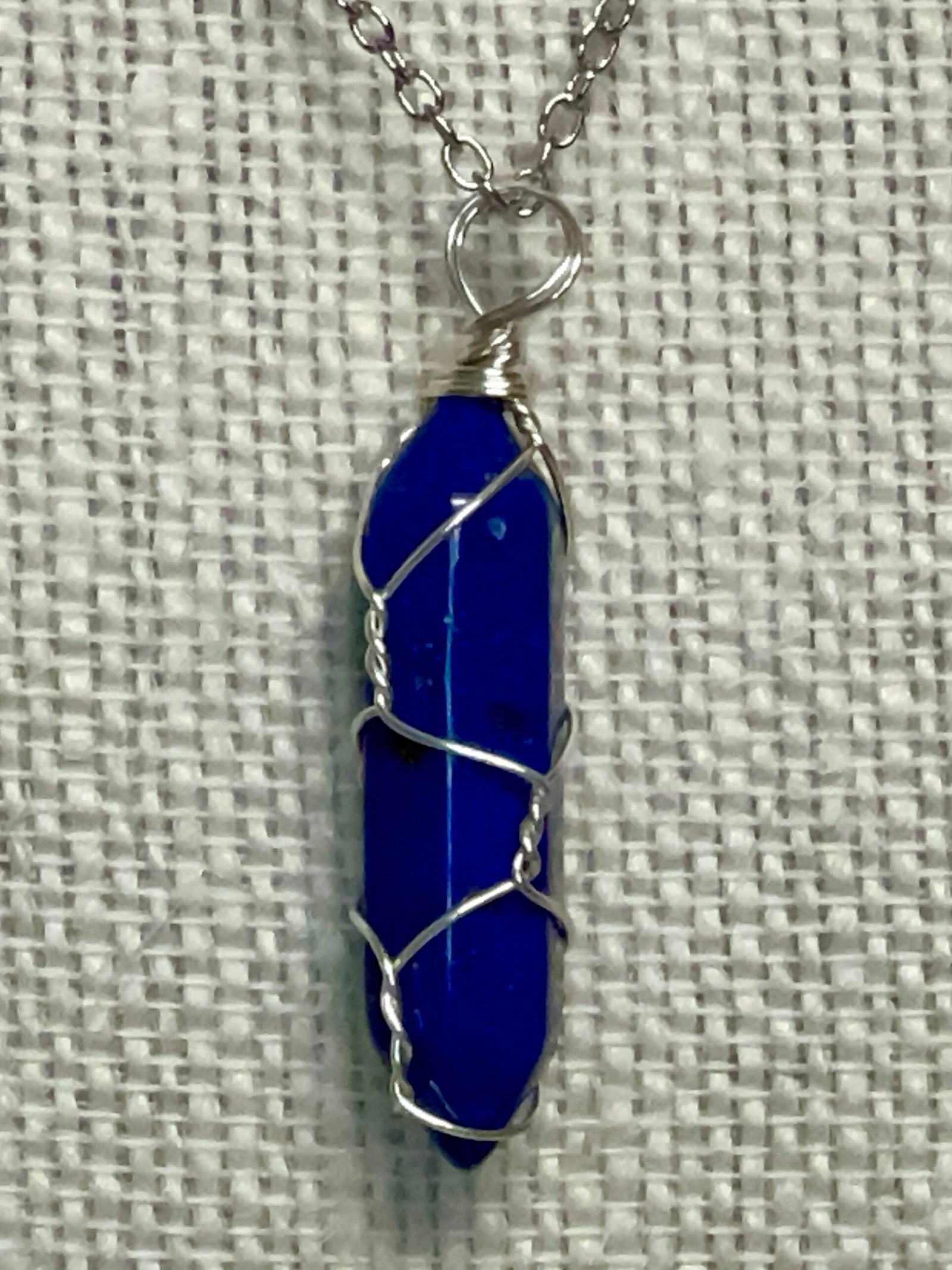 Silver wire-wrapped gemstone necklace with deep blue crystal point pendant
