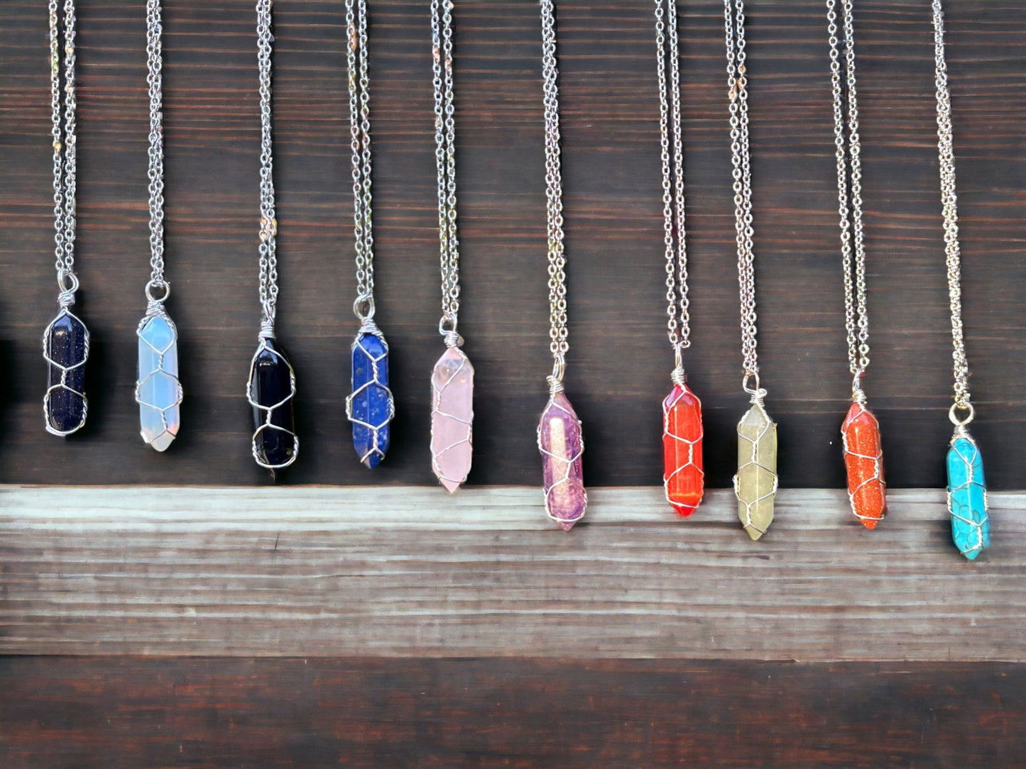 Silver wire-wrapped crystal gemstone necklaces set with assorted colored pendants on chains