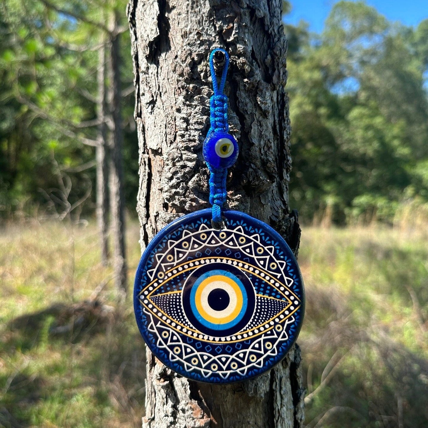 Evil eye ceramic wall hanging with blue round eye design and hanging cord