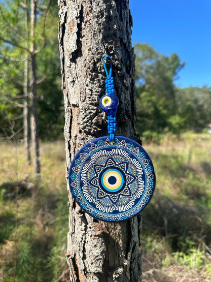 Blue ceramic evil eye wall hanging with yellow center, white mandala details and beaded tassel