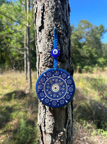 Round blue evil eye ceramic wall hanging with white floral mandala pattern and hanging charm