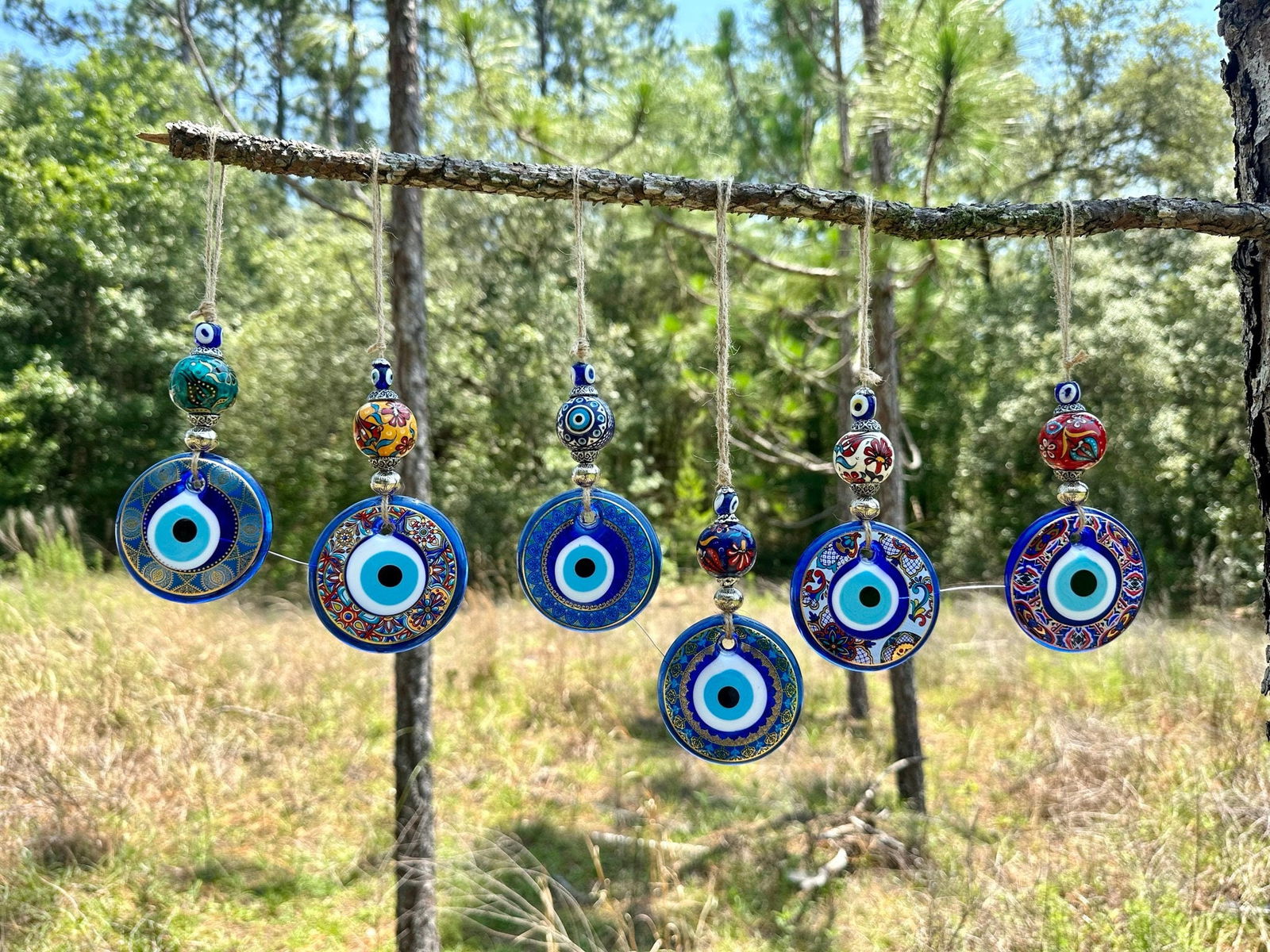 Blue and teal ceramic evil eye wall hanging with multiple round painted charms on strings