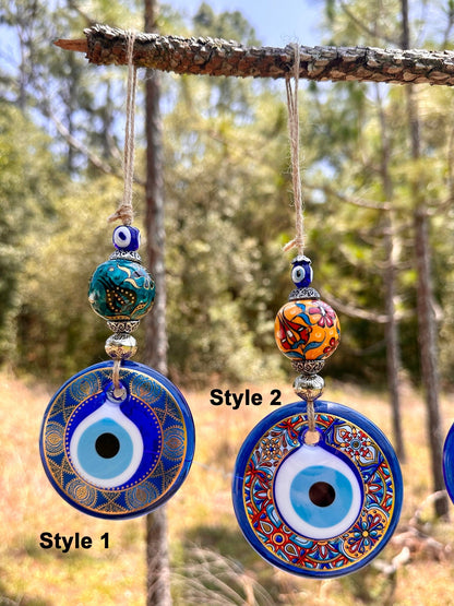 Ceramic evil eye wall hanging with two hanging round blue charms and bead accents