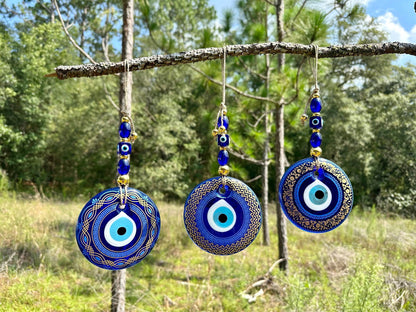 Three round blue evil eye pendants on a hanging cord with small blue bead accents