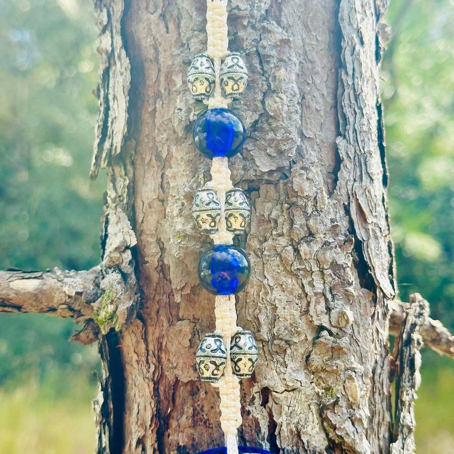Row of blue glass and silver-toned beads ending in blue evil eye charm
