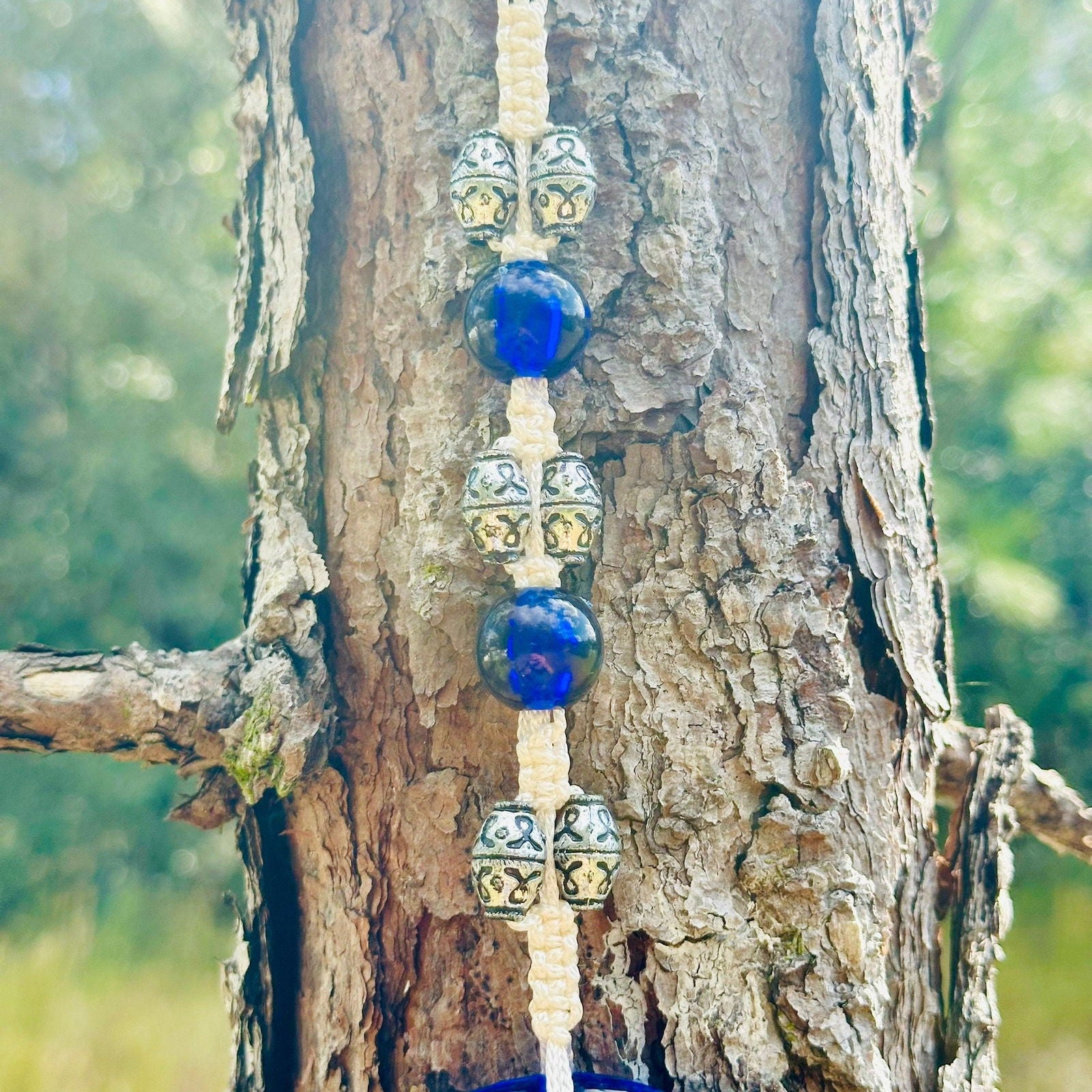 Row of blue glass and silver-toned beads ending in blue evil eye charm