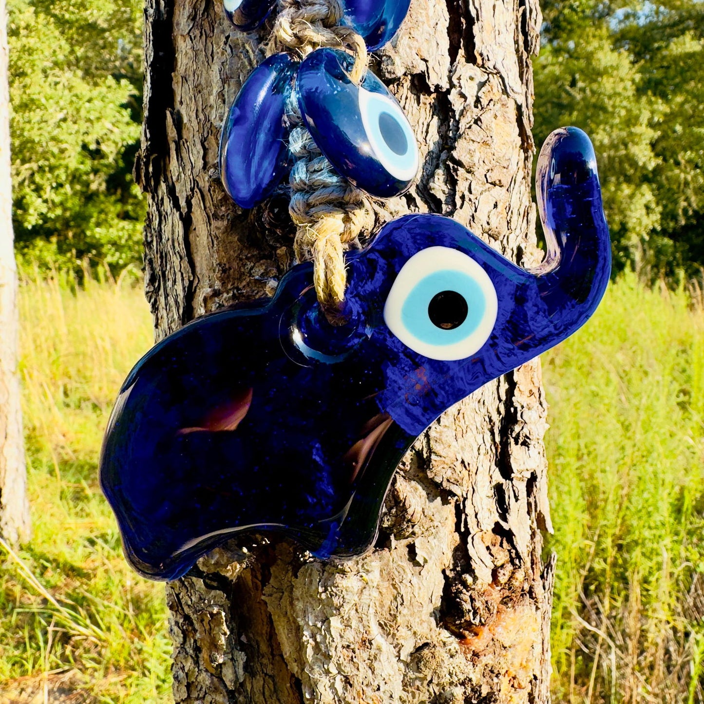 Blue evil-eye elephant figurine charm with raised trunk, hanging on rope