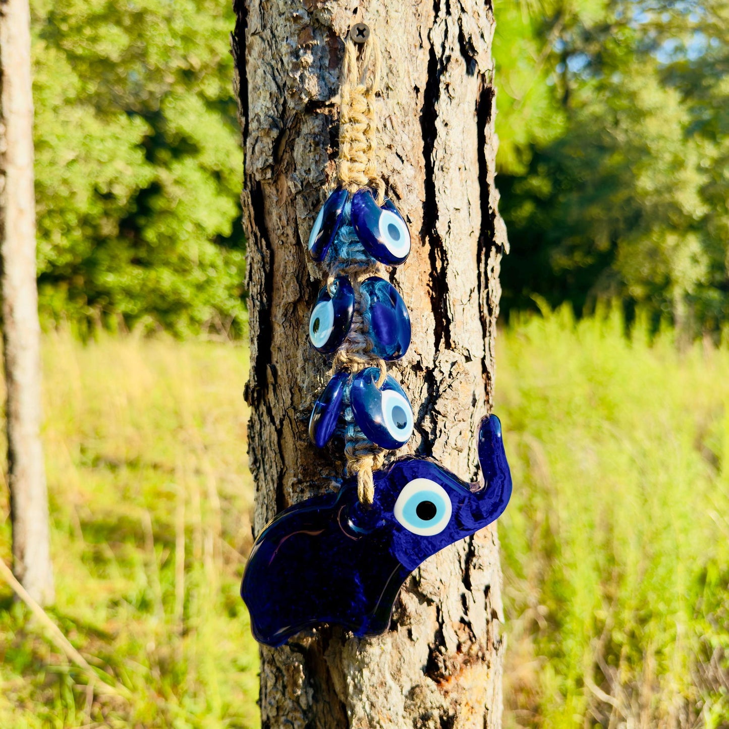 Blue elephant amulet with evil-eye beads hanging on rope, wall decor
