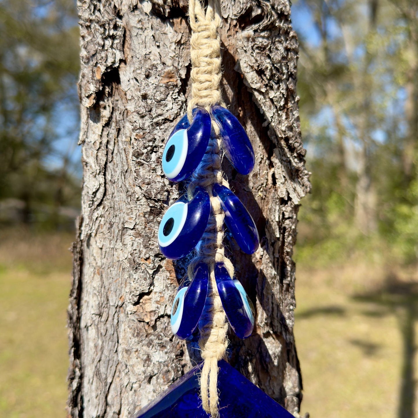 Cluster of blue evil eye glass charms with white eyes on macrame cord loop.