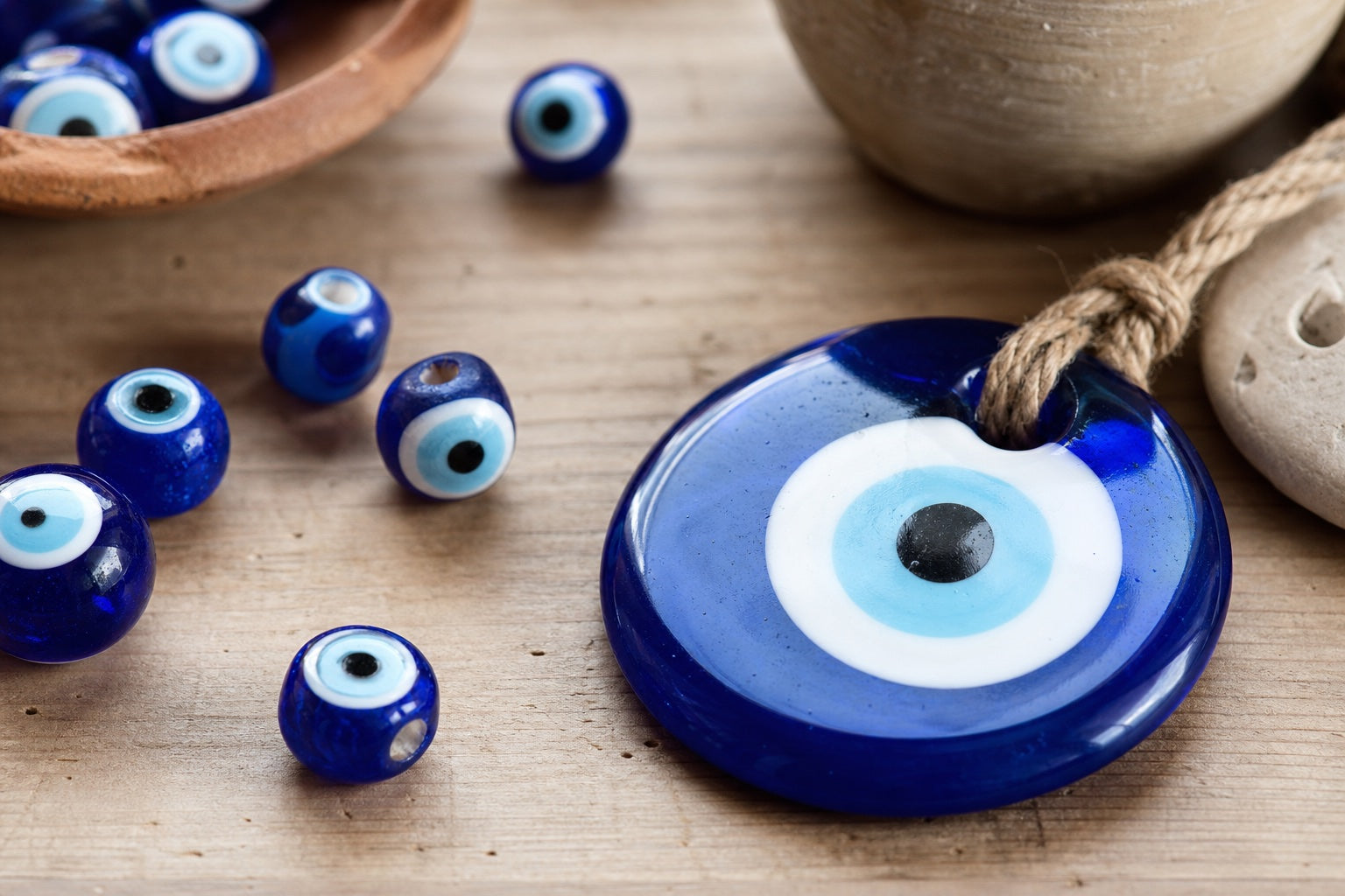 Handmade blue glass Nazar wall charm and small eye beads on an artisan table